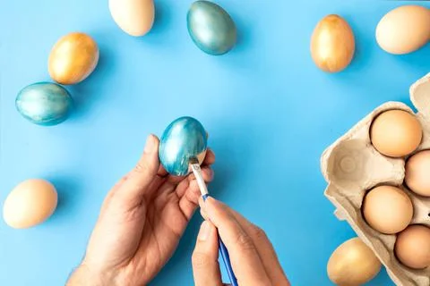 Preparing for Easter. Father painting Easter eggs on blue background. Easter day Stock Photos