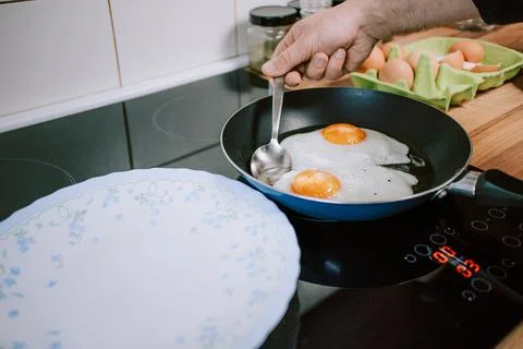 Preparing eggs for breakfast. Overhead view of black kitchen stove. Stock Photos