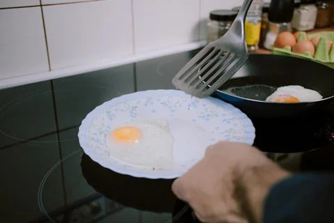 Preparing eggs for breakfast. Overhead view of black kitchen stove. Stock Photos