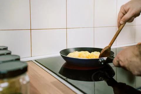 Preparing eggs for breakfast. Overhead view of black kitchen stove with fryin Stock Photos