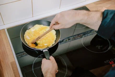Preparing eggs for breakfast. Overhead view of black kitchen stove  Stock Photos