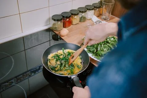Preparing eggs with spinach for breakfast. Overhead view. Stock Photos