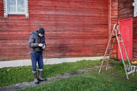 Preparing an electric drill for outdoor installation work, man in warm clot.. 写真素材