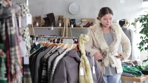 Preparing for fall and winter - girl try fur coat in a clothes store Stock Footage 346125476