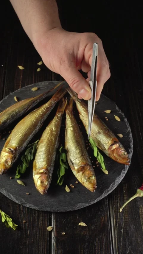 Preparing fish on a black plate with fresh herbs in a kitchen setting during Stock Footage 329041828