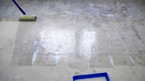 Preparing the floor for pouring, priming the floor. A worker using a roller p Stock Photos
