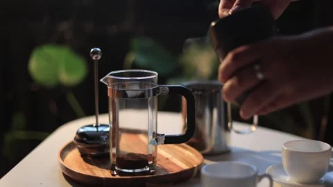 Preparing fresh coffee with a French press and steaming hot water in a cozy Stock Footage 338990579