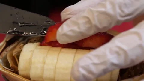 Preparing a Fresh Fruit Creep with Bananas and Strawberries close-up Stock Footage 345692171