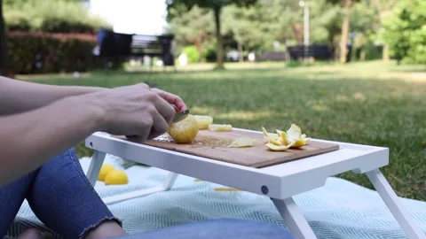 Preparing fresh lemon slices in a park setting on a sunny afternoon Stock Footage 297368519