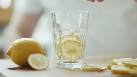 Preparing Fresh Lemon Water: Man's Hand Dropping Fruit and Pouring Mineral Water Video stock 332679416