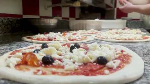 Preparing Fresh Pizzas With Cheese and Olives in a Busy Kitchen in Italy at Stock Footage 330794617