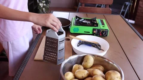 Preparing fresh potatoes by grating for a delicious meal outside Stock Footage 297358571