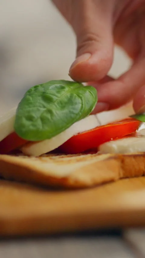 Preparing a fresh vegetable sandwich with layers of tomato cheese spinach an Stock Footage 331720578