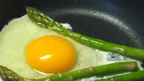 Preparing fried egg with fresh asparagus on frying pan Stock Footage 142400144