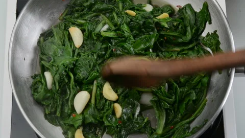 Preparing garlic sauteed spinach dish Stock Footage 148225614