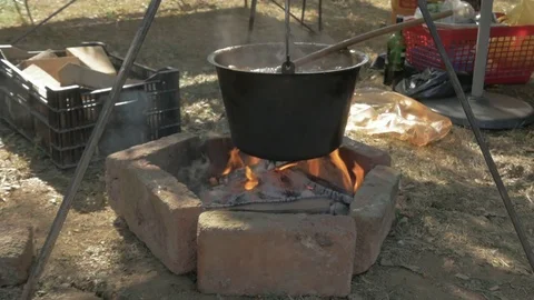 Preparing goulash or beef stew, boiling water in pot above firewood, outdoors. Video stock 81545660