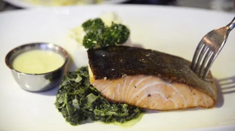 Preparing grilled salmon steak served with stirred spinach Stock Footage 63303348