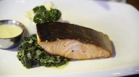 Preparing grilled salmon steak served with stirred spinach Stock Footage 63303361