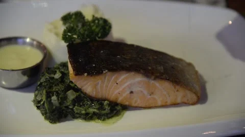 Preparing grilled salmon steak served with stirred spinach time-lapse Stock Footage 63352585