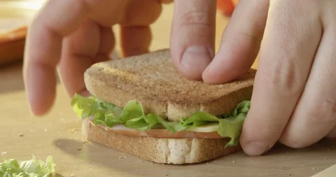 Preparing Ham and Cheese Sandwich with Lettuce and Toast Bread and Bitting Stock Footage 128648525