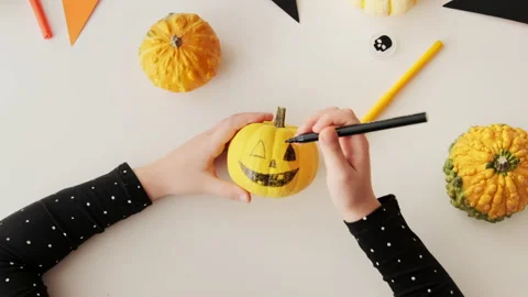 Preparing for holiday Halloween. Flat lay hands drawing scary face pumpkin Stock Footage 161964181