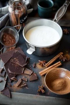 Preparing hot chocolate - a small pan of milk, cocoa powder, dark chocolate b Stock Photos