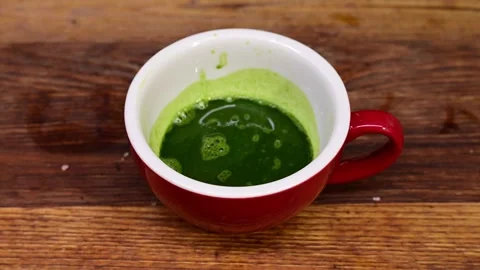 Preparing hot matcha tea in a ceramic mug on a wooden table 스톡 동영상 324612630