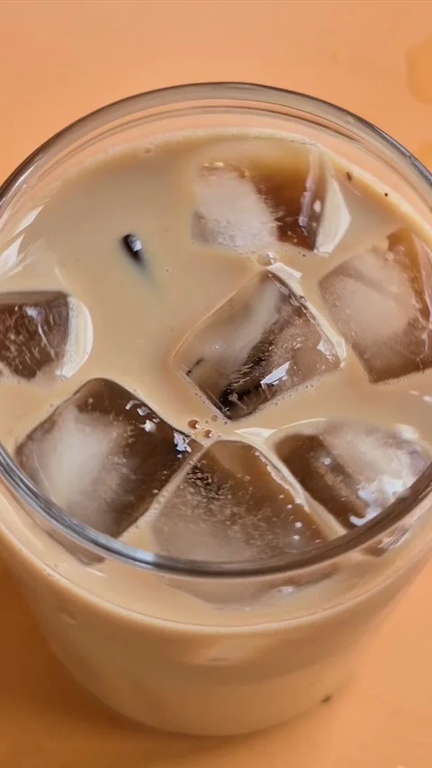 Preparing iced coffee with milk and ice in a glass cup Stock Footage 304667045