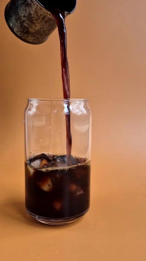 Preparing iced coffee with milk and ice in a glass cup Stock Footage 304667057
