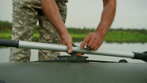 Preparing an inflatable boat for launching. The man screws the paddles Stock Footage 219777385