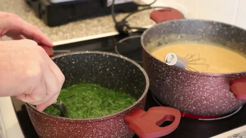 Preparing ingredients for salmon and spinach lasagna in pots on a stove Stock Footage 232005236