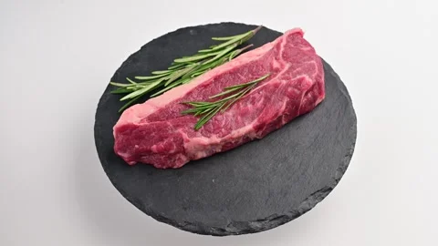 Preparing a juicy steak on a slate platter garnished with fresh rosemary for a Stock Footage 305233208