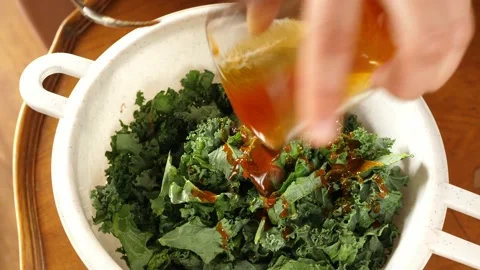 Preparing kale chips add adding spices salt mix mixing Stock Footage 138097960