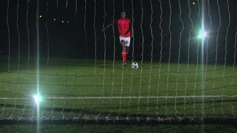 Preparing to kick ball, soccer player in red uniform aiming at goal net Видео 305078478