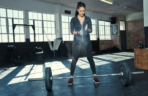 Preparing to lift some weights. a young woman dusting her hands with chalk Stock Photos