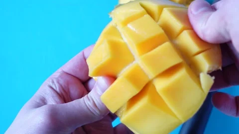 Preparing mango cubes by hand on bright blue background Stock Footage 335216746