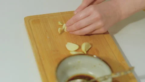 Preparing marinade for meat in the kitchen. Cutting garlic Stock Footage 256456536