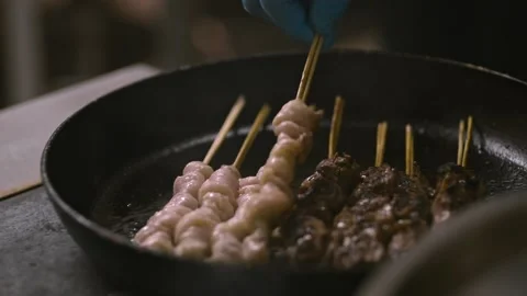 Preparing meat in frying pan roasting hot grilling meat chicken on stick lrrl Stock Footage 130497638
