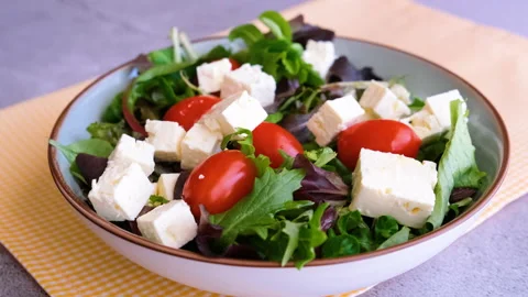 Preparing a Mediterranean salad, lettuce, tomatoes and feta cheese Stock Footage 150973888