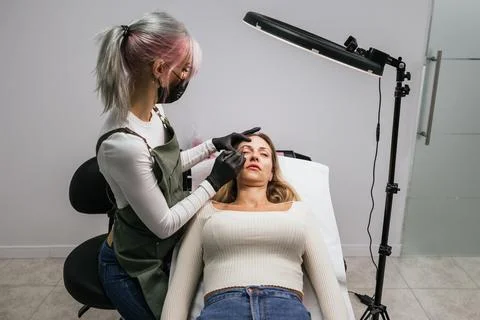 Preparing for microblading, careful eyebrow design in cosmetic studio Stock Photos
