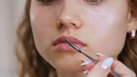 Preparing the model's skin for applying makeup. Lip treatment with a spatula and Stock Footage 128455458