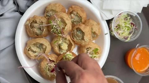 Preparing pani puri and gol gappe in a plate by adding salad into it. Stock Footage 296883633