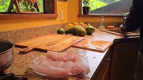 Preparing parrot fish fillets in a vibrant kitchen setting Stock Footage 296262704
