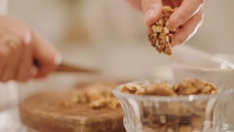 Preparing pie topping with walnuts. Hands scooping chopped nuts into dish Stock Footage 346394842