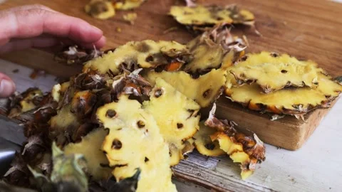 Preparing a pineapple. Peelings and waste being cleared from a wooden cutti.. Stock-Footage 280324836