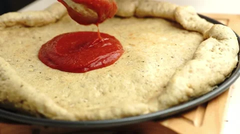 Preparing pizza pie with tomato sauce and spreading the saucy mixture with a  Stock Footage 68752861
