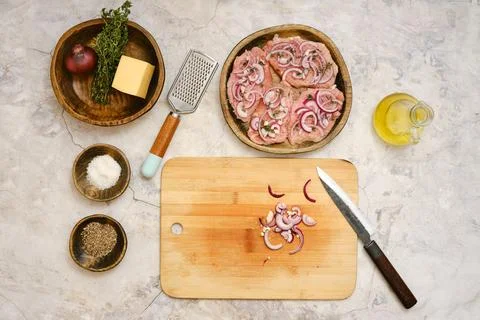 Preparing pork chops with onions and cheese on a wooden cutting board in a .. Foto stock