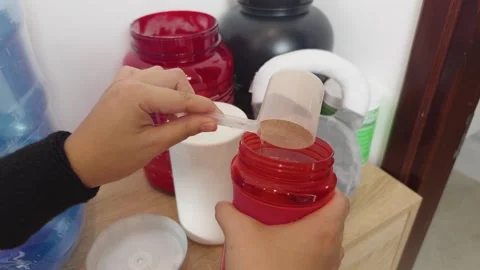 Preparing a protein shake, scooping supplement powder into a shaker bottle, Stock Footage 340963017