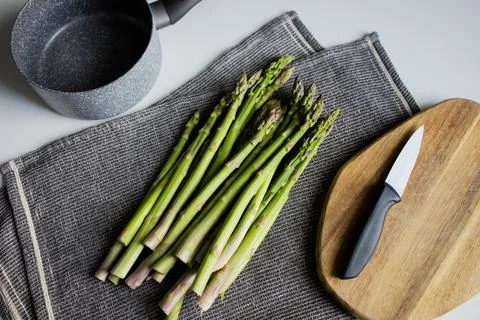 Preparing raw asparagus for cooking at the kitchen Stock Photos