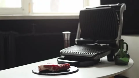 Preparing raw steak for cooking on an electric grill with olive oil Vidéo 342280630